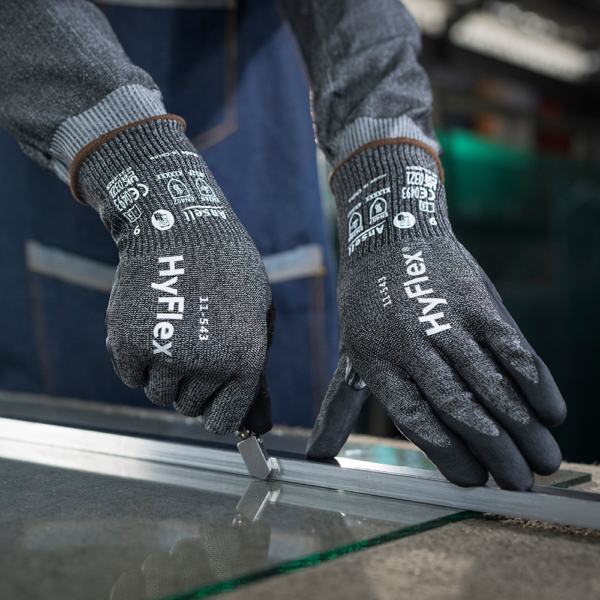 Close-up of Ansell HyFlex 11-543 gloves being used to cut glass with a handheld glass cutter.