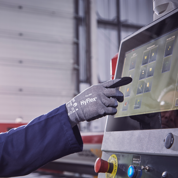 Worker wearing Ansell HyFlex 11-581 glove using touchscreen machine in an industrial setting