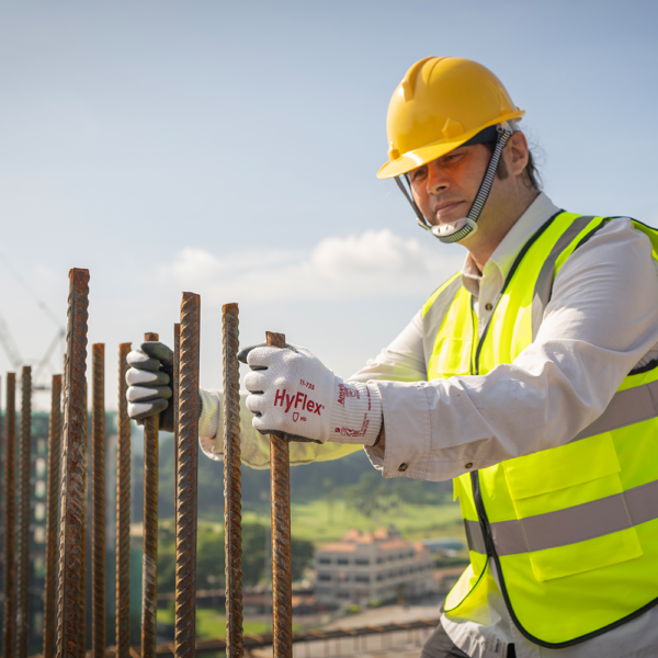 Construction worker using Ansell HyFlex 11-735 gloves while aligning rebar on a building site