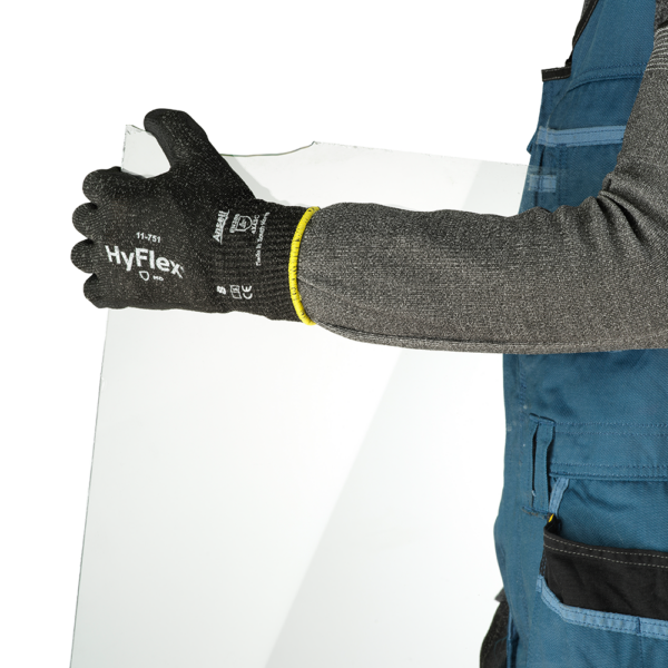 Worker wearing Ansell HyFlex 11-751 gloves while handling a glass panel for cut protection