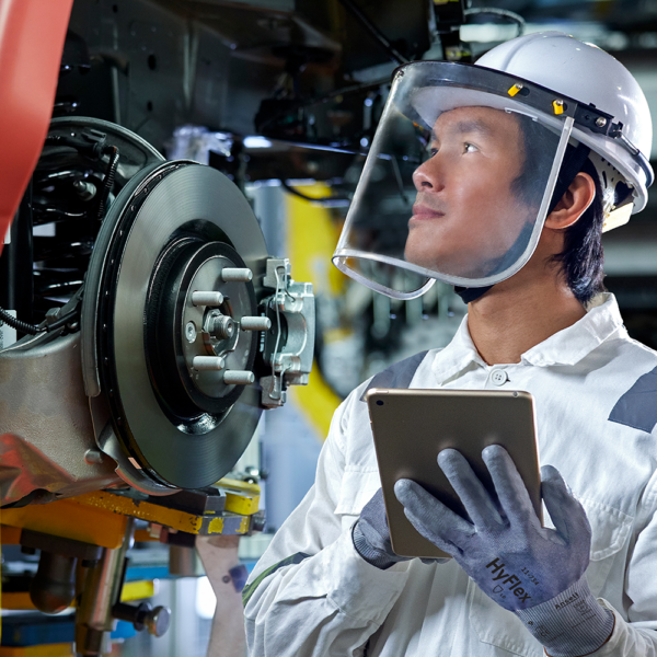 Worker inspecting machinery and holding tablet while wearing Ansell HyFlex 11-754 gloves.