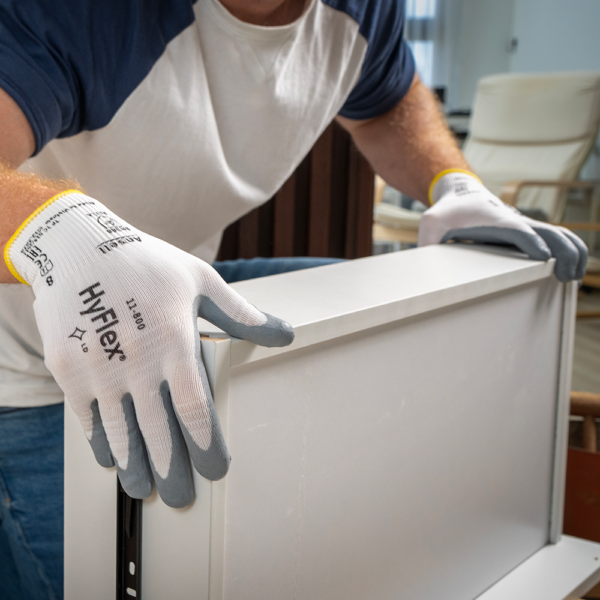Worker wearing HyFlex 11-800 gloves while assembling white furniture, highlighting dexterity and grip control.