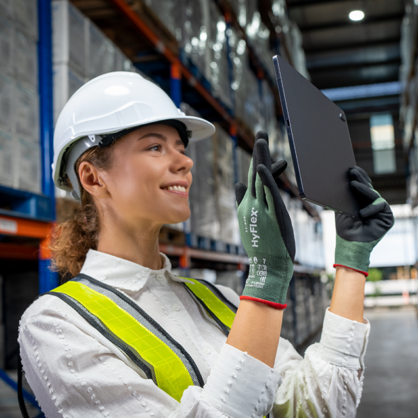 Warehouse worker wearing HyFlex 11-842 gloves using tablet for inventory management