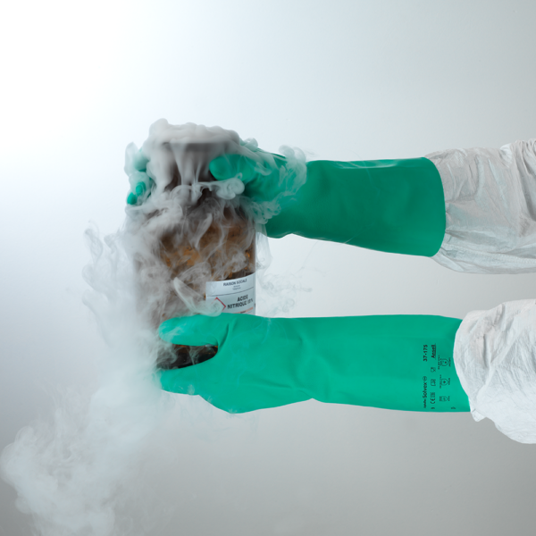 AlphaTec Solvex 37-175 gloves protecting hands while handling a cold, smoking container of nitric acid.