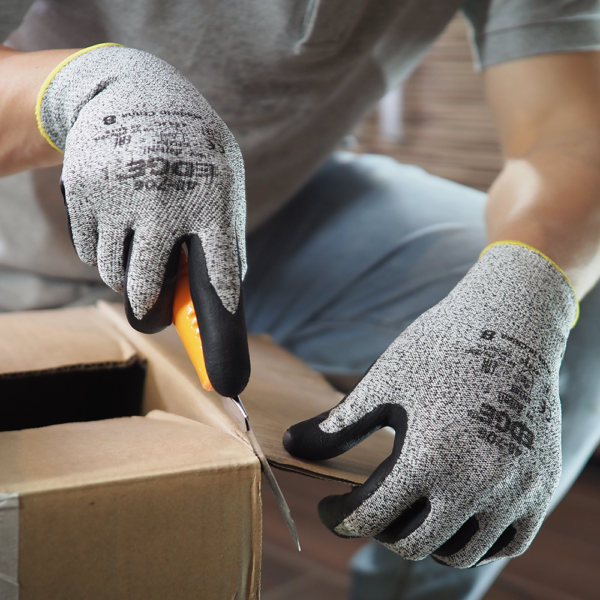 Worker wearing Ansell EDGE 48-706 gloves while opening a cardboard box with a safety knife