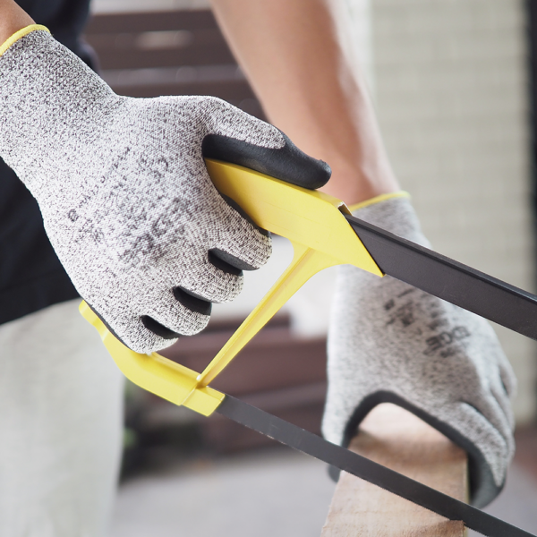 Worker using a handsaw while wearing Ansell EDGE 48-706 cut-resistant gloves for hand protection