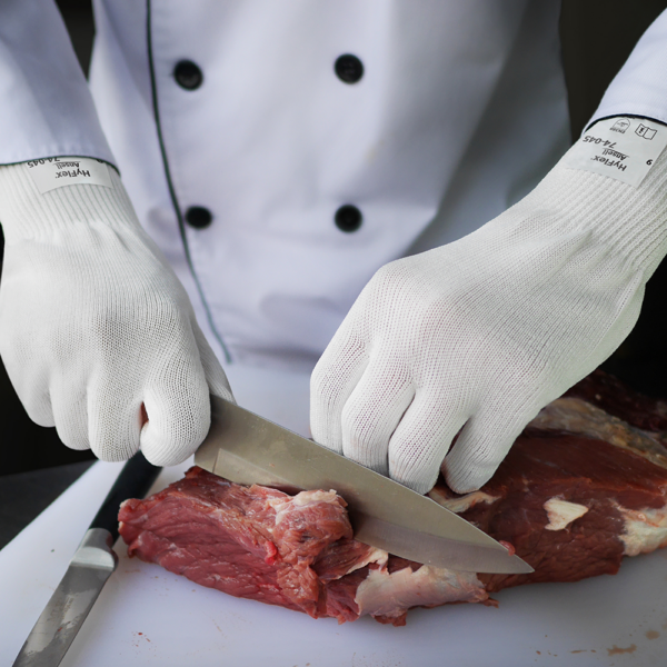 Ansell HyFlex 74-045 gloves in use by chef slicing meat, demonstrating food-safe cut resistance