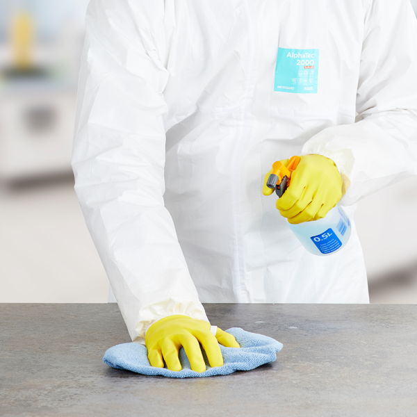 Worker cleaning surface while wearing AlphaTec 87-190 gloves and AlphaTec 2000 coveralls for chemical protection