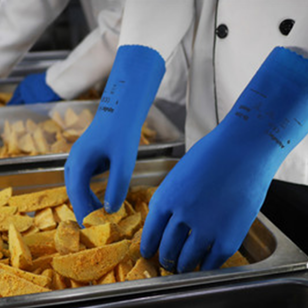 AlphaTec 88-350 blue gloves being worn by food service workers handling seasoned potato wedges in trays.