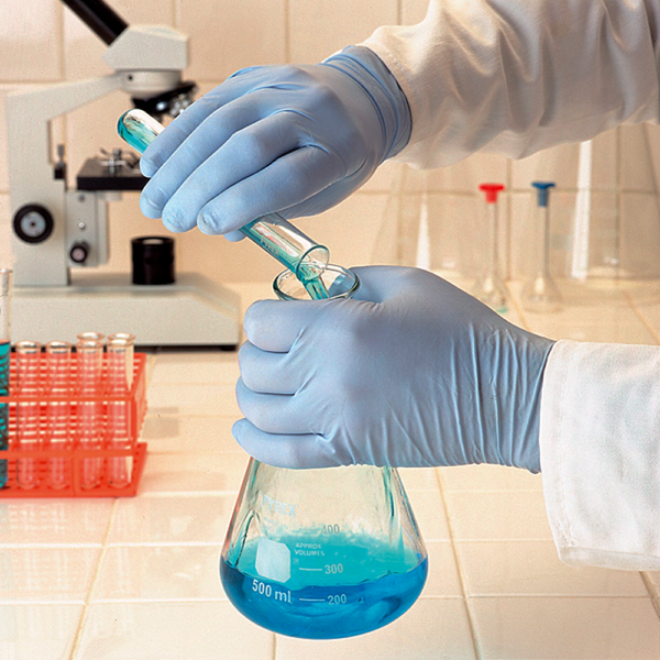 Gloved hands handling laboratory glassware, demonstrating chemical resistance of nitrile gloves.