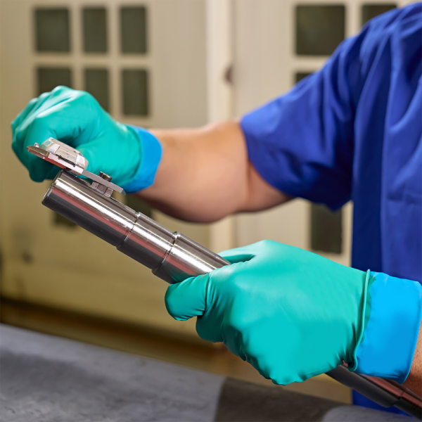 Worker using Microflex 93-260 gloves for precision handling of metal components in industrial setting