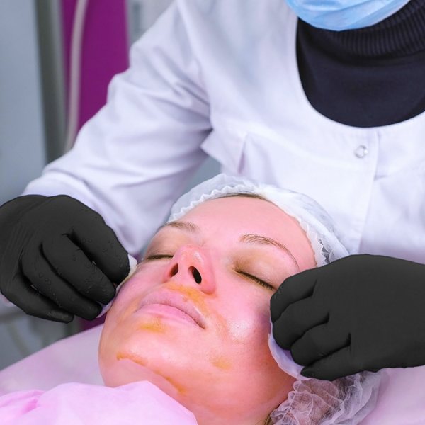 Beauty technician applying a facial treatment while wearing Microflex 93-852 gloves