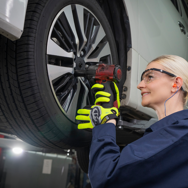 Worker using Ringers R138 gloves while tightening wheel nuts with impact wrench in automotive workshop