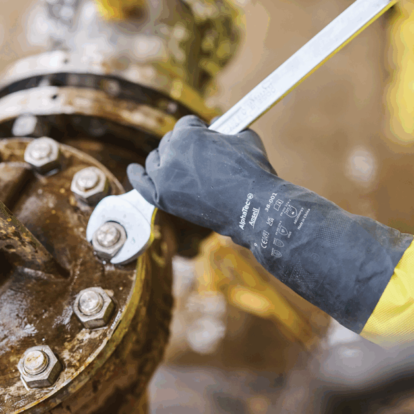 Worker wearing Ansell AlphaTec 38-001 chemical resistant gloves while tightening bolts on industrial machinery