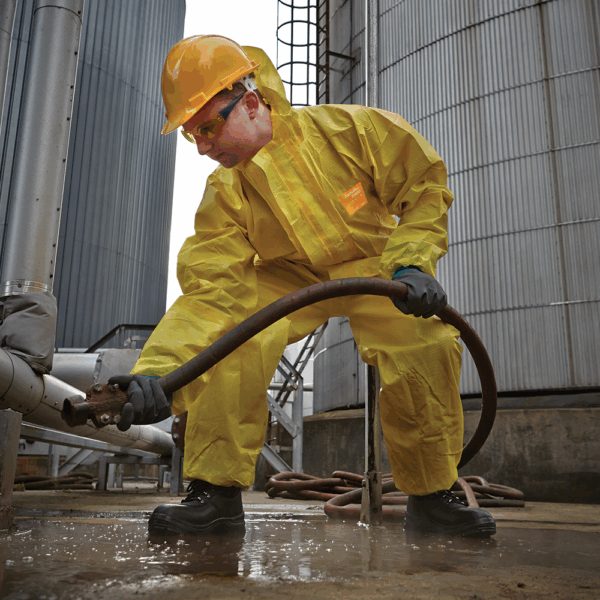 Industrial worker wearing AlphaTec 58-201 chemical resistant gloves and protective suit while handling hoses on site