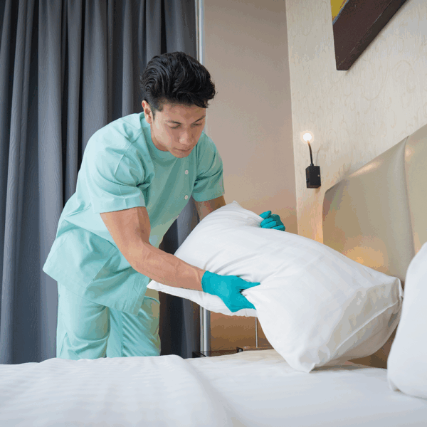 Hospitality worker wearing Ansell TouchNTuff 92-600 nitrile gloves while making a hotel bed for hygiene protection