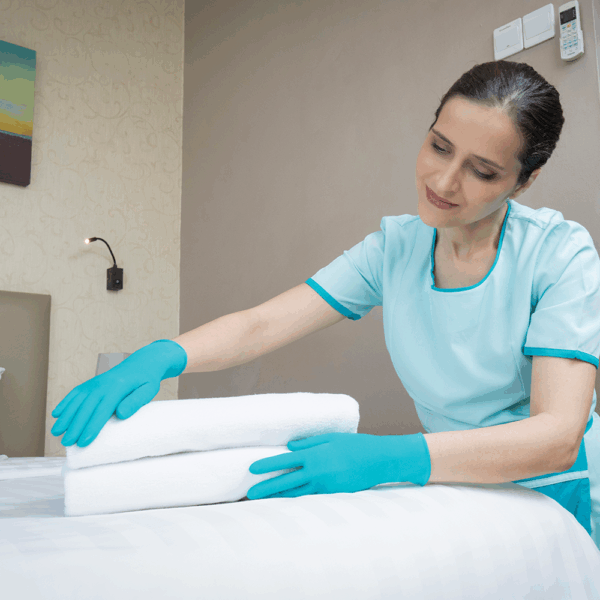 Housekeeping staff using Ansell TouchNTuff 92-600 nitrile gloves while folding towels to maintain hygiene and hand protection