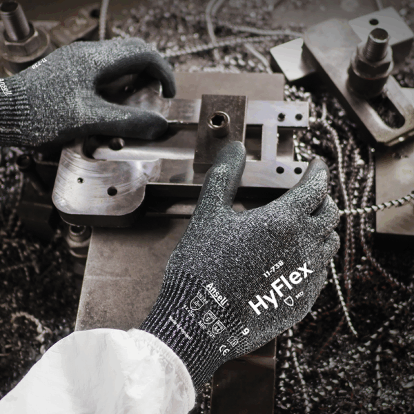 Worker wearing Ansell HyFlex 11-738 gloves operating metal machinery – high-dexterity cut-resistant gloves for industrial tasks.