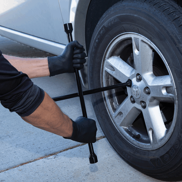Mechanic wearing Ansell MICROFLEX 93-732 black nitrile gloves tightening wheel nuts on a vehicle.
