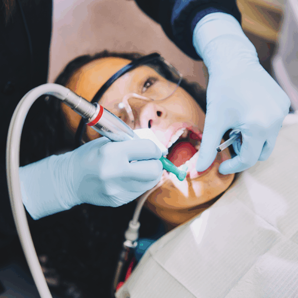 Dentist wearing Ansell MICROFLEX 93-833 nitrile gloves performing a dental cleaning on a patient.